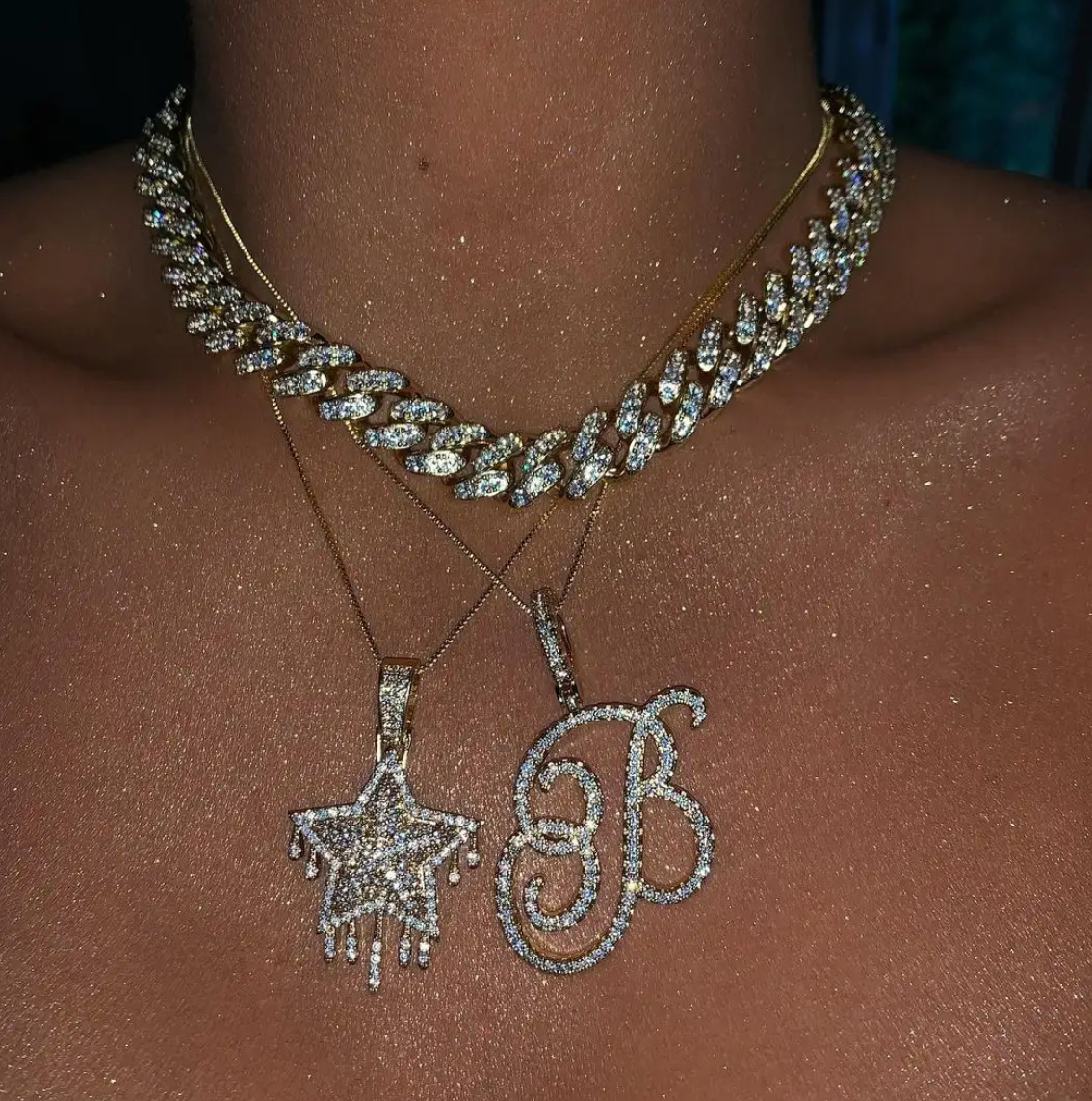 Personalized crystal script initial necklace styled with layered sparkling pendant necklaces and Cuban link chain