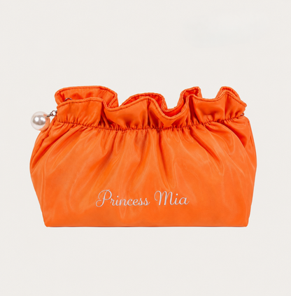 Orange drawstring bag with 'Princess Mia' embroidery on a beige background