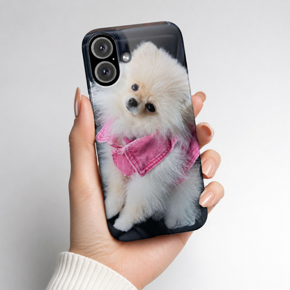 Phone case with a dog design held by a hand against a light gray background